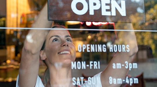 Woman inside shop putting up open sign