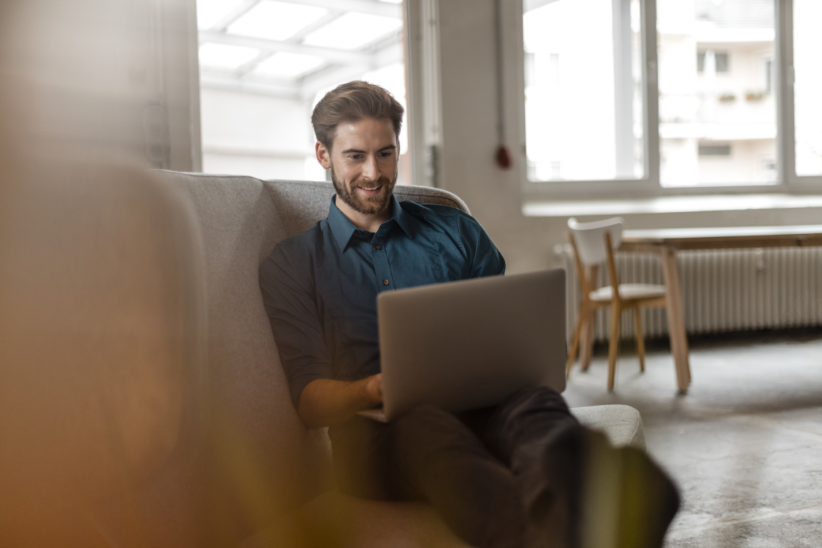 man with laptop sitting on soft in office