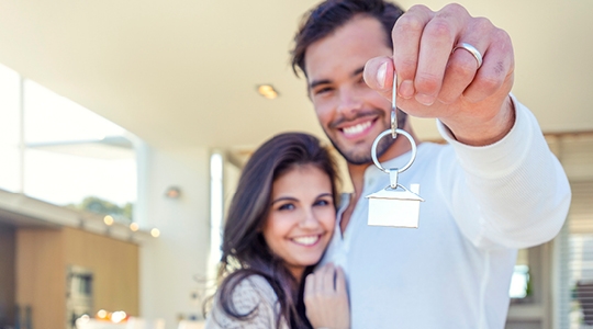 Couple in kitchen holding house keyring 