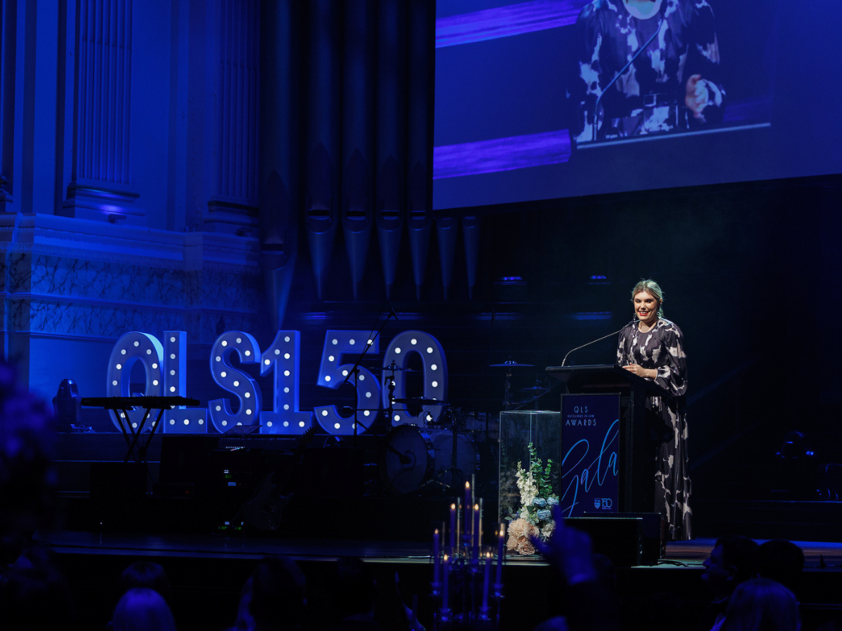 Photograph of Arabella Kullack on blue lit stage giving speech