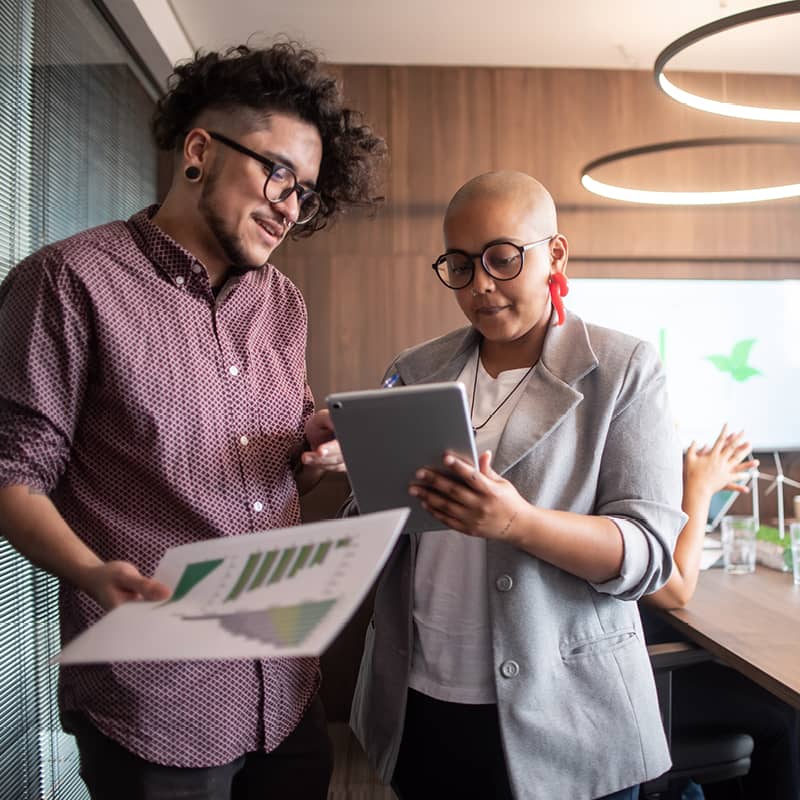 Two people looking over an ipad and one person is also holding papers