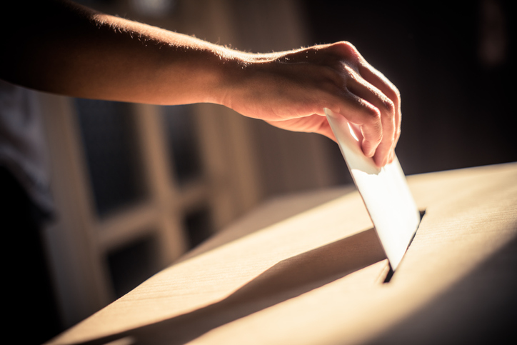 Hand putting a ballot in a box