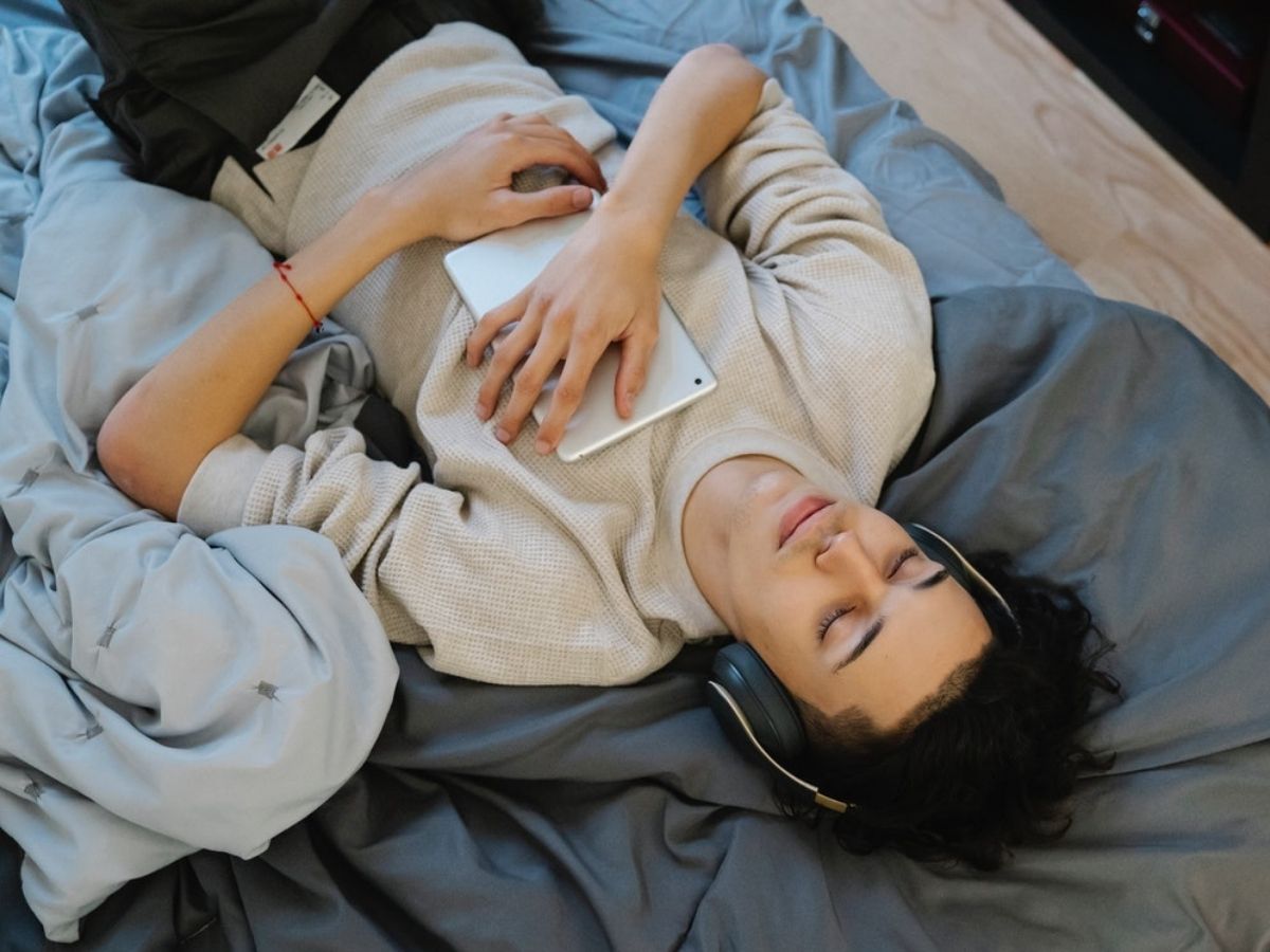 Man lying back on bed wearing headphones